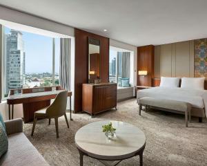 a hotel room with a bed and a desk and a table at Grand Hyatt Jakarta in Jakarta