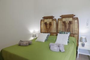 a green bed with two pillows on top of it at Trulli Dimore - Saveni in Castellana Grotte