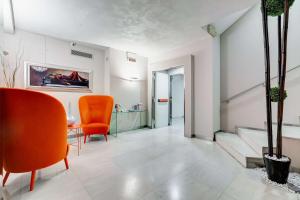 Best Western Cinemusic Hotel في روما: غرفة معيشة مع كراسي برتقالية وطاولة