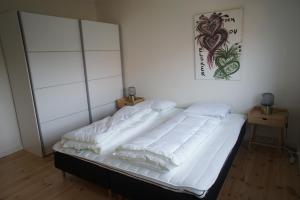 1 cama con sábanas blancas y almohadas en una habitación en (id.023) Spangsberggade 24. 2 tv, en Esbjerg