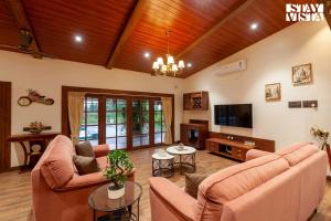 a living room with two couches and a tv at Golden Sunsets by StayVista - Refreshing pool, serene lawn - your tranquil retreat in Alibaug