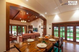 a dining room and living room with a wooden table at Golden Sunsets by StayVista - Refreshing pool, serene lawn - your tranquil retreat in Alibaug