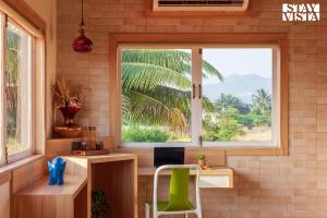a window in a room with a desk and a chair at Golden Sunsets by StayVista - Refreshing pool, serene lawn - your tranquil retreat in Alibaug +20 photos