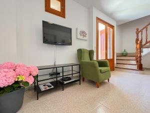 a living room with a green chair and a television at Finca Margarita Cas Concos in Caʼs Concos