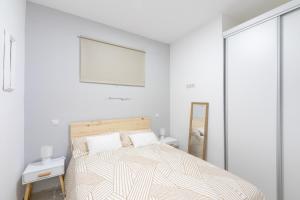 Habitación blanca con cama y espejo en Market Martinez de la Riva II, en Madrid