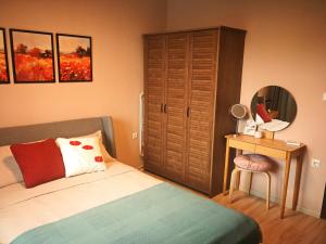 a bedroom with a bed and a table with a mirror at Kalina Apartment Kazanlak in Kazanlŭk