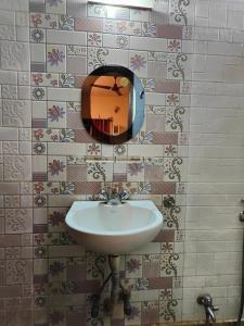 uma casa de banho com um lavatório e um espelho na parede em AMIT HOTEL em Calcutá