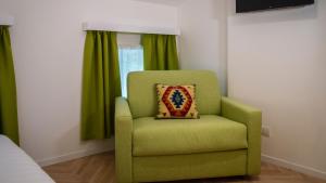 1 dormitorio con silla verde y almohada en B&B PIEDICASTELLO en Trento