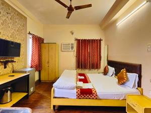 a bedroom with a bed and a desk and a television at AMIT HOTEL in Kolkata