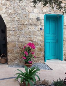 a blue door on the side of a stone building with flowers at Bella Casetta Guest House in Famagusta