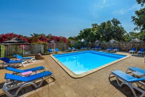 une piscine avec des chaises longues bleues et un complexe dans l'établissement Camping U Pirellu, à Porto-Vecchio