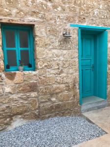 a stone building with a blue door and two windows at Bella Casetta Guest House in Famagusta