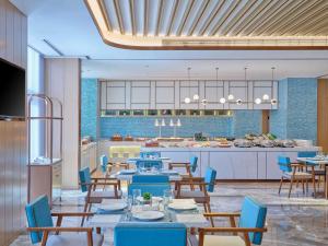 uma sala de jantar com mesas e cadeiras e uma cozinha em Hilton Garden Inn Xiamen Tong'An em Xiamen