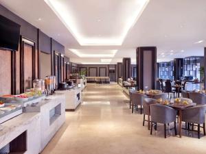 a restaurant with tables and chairs and a buffet at Grand Mercure Solo Baru in Solo