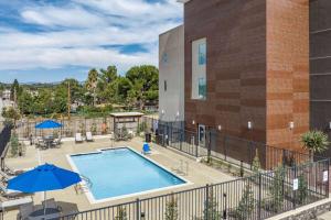 a swimming pool with umbrellas and a building at La Quinta Inn & Suites by Wyndham Yucaipa 