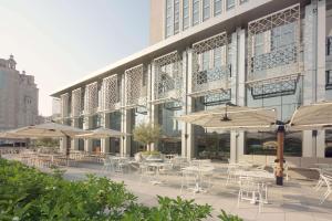 a patio with tables and umbrellas in front of a building at Rove Downtown in Dubai