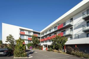 an apartment building with red balconies and a parking lot at Best Western Les Aureliades Saint Nazaire in Trignac