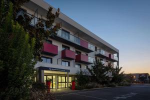 a building with red balconies on the side of it at Best Western Les Aureliades Saint Nazaire in Trignac