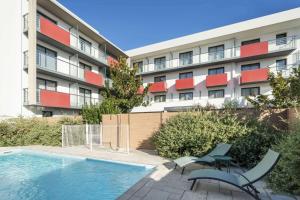 un edificio de apartamentos con piscina frente a un edificio en Best Western Les Aureliades Saint Nazaire, en Trignac