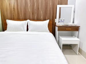 a bedroom with a white bed and a wooden headboard at Milanesa Hotel and Apartment in Vung Tau