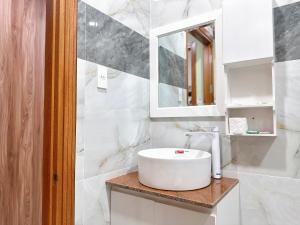 a white bathroom with a sink and a mirror at Milanesa Hotel and Apartment in Vung Tau