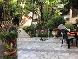 eine Terrasse mit Stühlen, Tischen und Topfpflanzen in der Unterkunft Kutaisi City Heart Apartment in Kutaissi