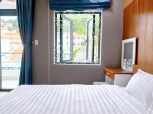 a bedroom with a bed and a window with blue curtains at Milanesa Hotel and Apartment in Vung Tau