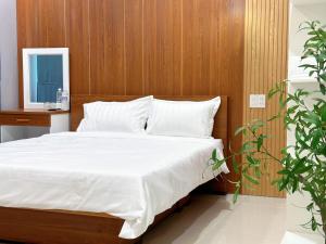 a bedroom with a bed with white sheets and wooden walls at Milanesa Hotel and Apartment in Vung Tau