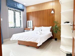 a bedroom with a large bed with a wooden headboard at Milanesa Hotel and Apartment in Vung Tau
