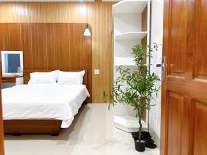 a bedroom with a bed and a potted plant at Milanesa Hotel and Apartment in Vung Tau