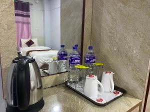 Hotel Kavya Inn في بهاراتبور: غرفة في الفندق مع مرآة وزجاجات الماء