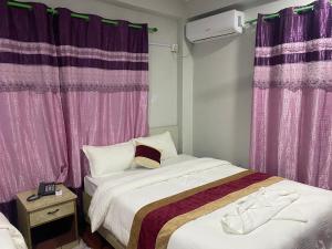 Hotel Kavya Inn في بهاراتبور: غرفة نوم بسريرين وستائر ارجوانية