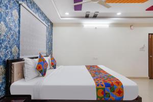 a bedroom with a white bed with blue walls at FabHotel Sri Karthikeya Grand in Hyderabad