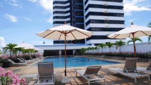 - une piscine avec des chaises et des parasols en face d'un bâtiment dans l'établissement Royal Phuket City Hotel - SHA Extra Plus, à Phuket