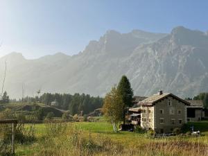 an old house in a field with mountains in the background at Chesa Klucker - Fextal in Fex