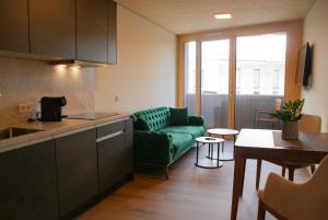 cocina y sala de estar con sofá verde en Aparthouse Leonhard en Feldkirch