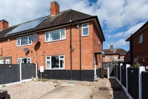 a red brick house with a solar roof at Bright and Warm 3-bed Home in Nottingham by Renzo, Free Driveway Parking, Close to Wollaton Park! in Nottingham