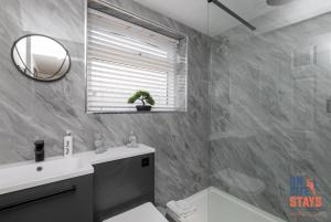uma casa de banho com um lavatório, um WC e um espelho. em OnSiteStays - Stylish 4 BR House with Beautiful Outdoor Space, Wi-Fi & Smart TVs em Dartford