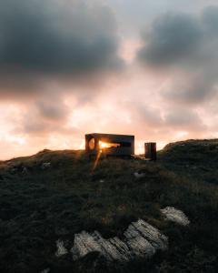 Cama abultada en la cima de una colina de hierba con la puesta de sol en Birdbox Reksta en Florø