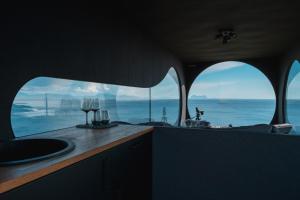 a bathroom with two wine glasses and a view of the ocean at Birdbox Reksta in Florø