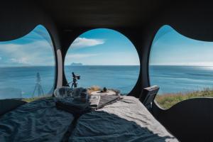a table with a view of the ocean from inside a tent at Birdbox Reksta in Florø