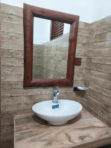 a bathroom sink with a mirror on a wooden wall at Nine Arch Gap in Ella