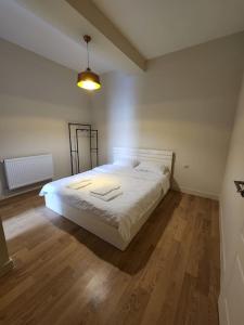 Schlafzimmer mit einem weißen Bett und Holzboden in der Unterkunft Tsereteli flatt 7 in Tbilisi City