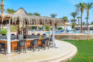 a bar at a resort with chairs and a pool at Jaz Fayrouz in Sharm El Sheikh