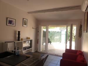 sala de estar con sofá rojo y puerta corredera de cristal en Petite maison avec terrasse et piscine en Beaucaire