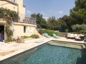 een zwembad in een tuin met stoelen en een huis bij Petite maison avec terrasse et piscine in Beaucaire