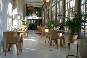 a dining room with tables and chairs and windows at Les Chambres du Cloître in Limoges