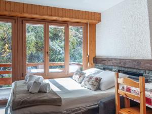 Ce lit se trouve dans un dortoir doté de fenêtres et d'une chaise. dans l'établissement Apartment Derborence 25 by Interhome, à Nendaz