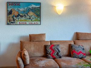 - un canapé brun dans le salon avec une photo sur le mur dans l'établissement Apartment Anemone 9 by Interhome, à Nendaz