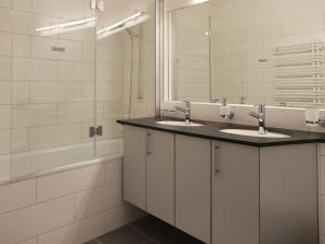 ein Badezimmer mit zwei Waschbecken, einem Spiegel und einer Badewanne in der Unterkunft Apartment Allod-Park-15 by Interhome in Davos